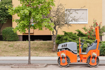 Eine kleine orange Dampfwalze am Strassenrand