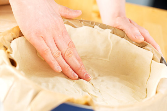 Hands of a cook forming pie dough