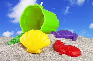 Fototapeta na wymiar children's toys on the sand on the blue sky