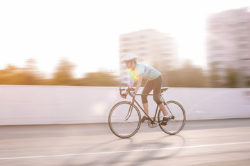 young female athlete racing on a bike. motion blurred image