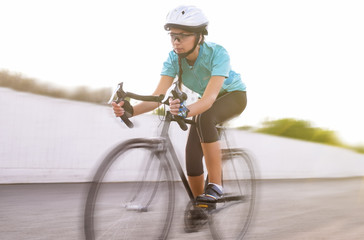 Naklejka premium portrait of young female athlete racing on a bike. motion blurre