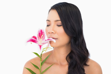 Obraz na płótnie Canvas Natural brown haired model smelling lily closing eyes