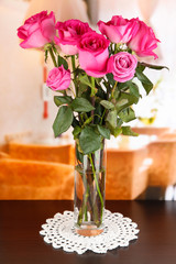 Beautiful pink roses in vase on table on room background