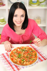 Obraz na płótnie Canvas Beautiful girl with delicious pizza on kitchen background