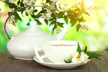 Cup of tea with jasmine, on bamboo mat, on bright background