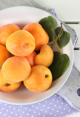 Apricots in plate on board on napkin on wooden table