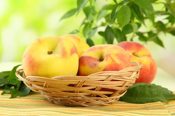 Ripe sweet peaches in basket on table, outdoors