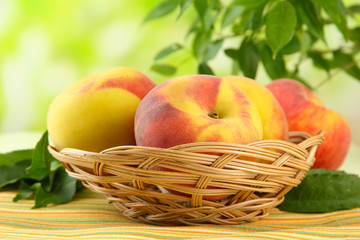 Ripe sweet peaches in basket on table, outdoors