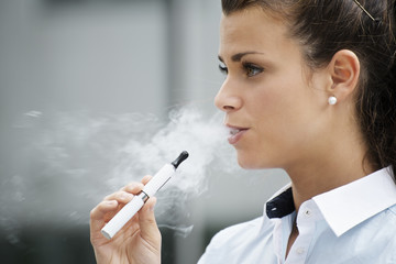 young woman smoking electronic cigarette outdoor office building - Powered by Adobe