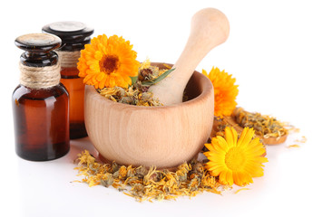 Medicine bottles and calendula flowers in wooden mortar