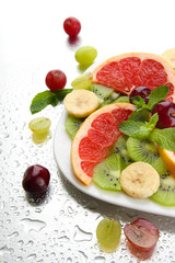 Assortment of sliced fruits on plate with drops