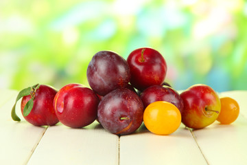 Ripe plums on wooden table on natural background