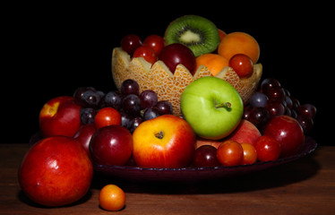 Fototapeta na wymiar Assortment of juicy fruits on wooden table, on dark background