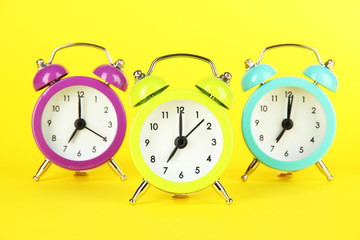 Colorful alarm clock on yellow background