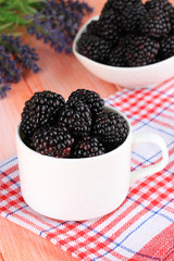 Sweet blackberries in cup on table close-up
