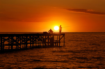 two fishermen on the bridge in the sea at sunrise