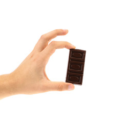 Hand holds dark chocolate bar.