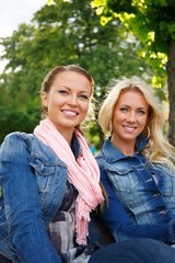 Two beautiful smiling young girl in jeans jackets 