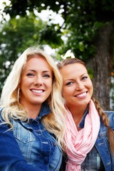 Two beautiful smiling young girl in jeans jackets 