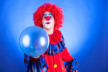 Smiling clown in studio with balloon