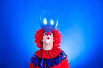 Smiling clown in studio with balloon