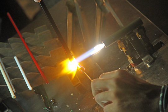 Glazier with gas torch lit while blending a piece of glass 1