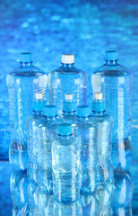 Water in different bottles on blue background