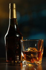 Glass of whiskey with bottle, on dark background
