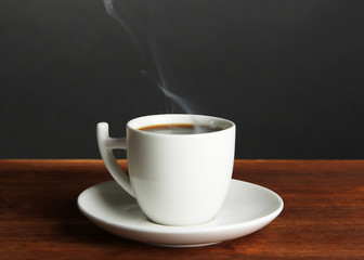 Cup of coffee on wooden table on black background