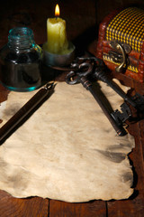 Old paper with ink pen near lighting candle on wooden table
