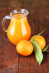 Full jug of tangerine juice, on wooden background