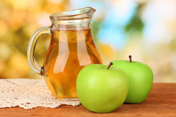 Full jug of apple juice and apple