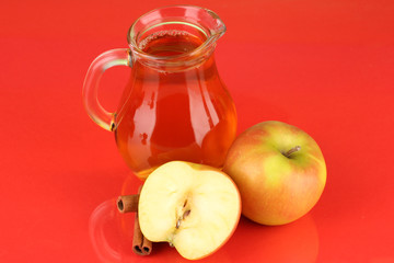 Full jug of apple juice and apple on color background