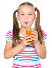 Little girl is drinking carrot juice