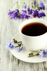 Cup of tea with chicory, on wooden background