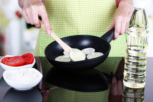 Hands cooking marrows in pan in kitchen