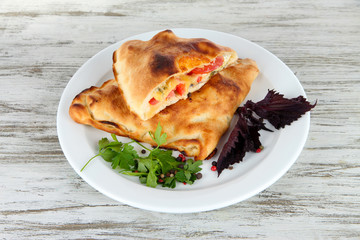Pizza calzones on plate on wooden table