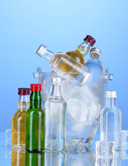 Minibar bottles in bucket with ice cubes,  on color background