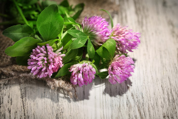 Clover flowers with leaves on wooden background