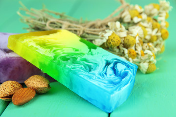 Pieces of handmade soap with herbs, on color wooden background