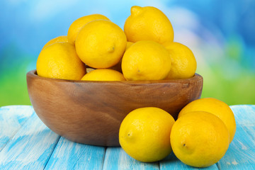 Ripe lemons in bowl on table on bright background