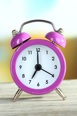 Alarm clock on table on bright background