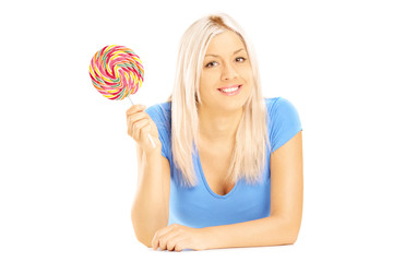 Blond female lying down with lollipop and looking at camera