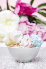 Fototapeta na wymiar Marshmallows in white ceramic bowl. Stunning pink peonies
