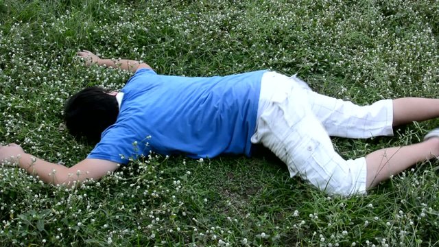 An Asian guy is drop dead on the grassy ground and twitching