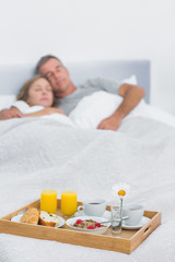 Obraz na płótnie Canvas Peaceful couple sleeping with breakfast tray on bed