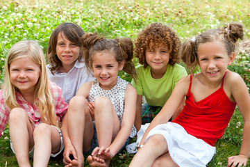 Children sitting together in flower field.