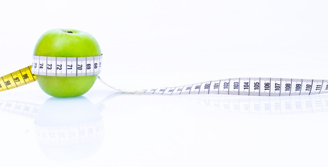 Concept of health apple with measuring tape on reflecting white 