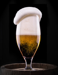 Frosty glass of light beer on black background