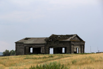 старый полуразрушенный деревянный дом стоит один в поле